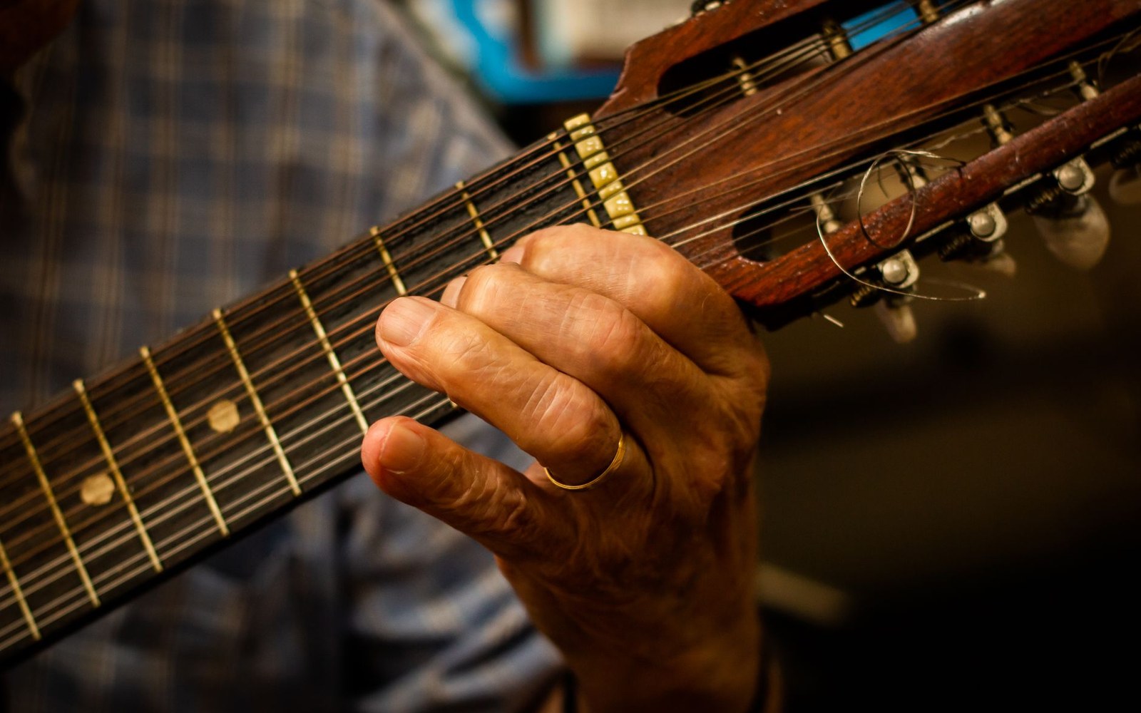 Close-up of an adult cuatro player's left hand fretting the instrument's neck during a joropo performance, Venezuela