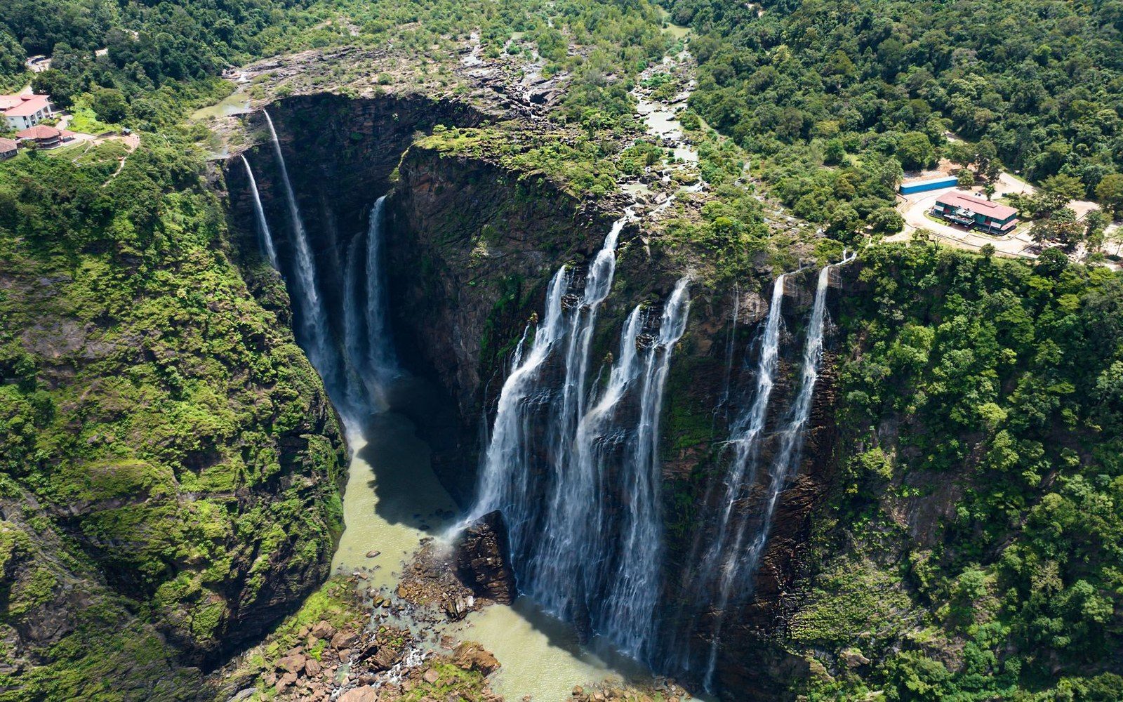 Aerial view of multiple waterfall streams cascading over a cliff into a jungle gorge