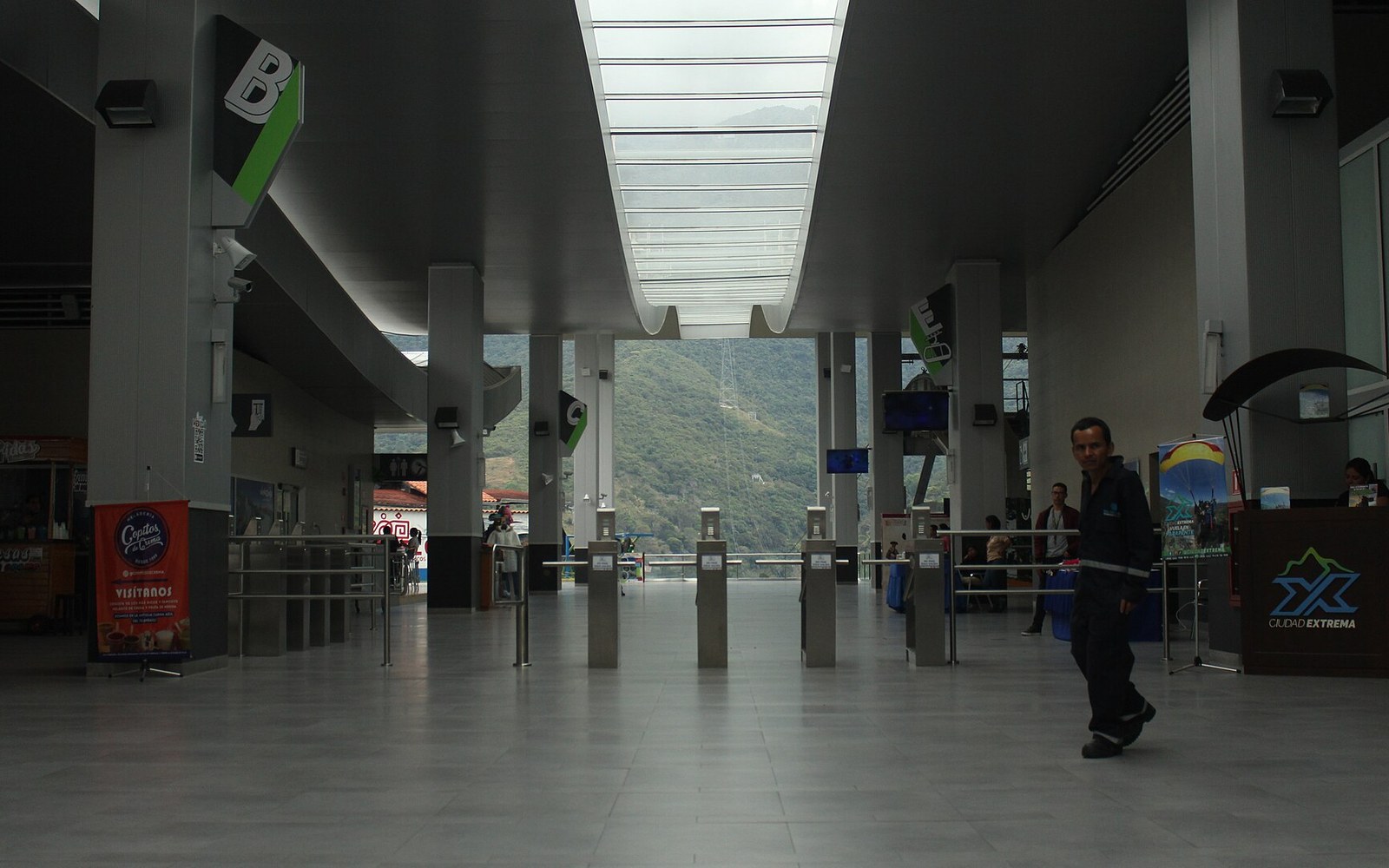 Turnstile gates lead through a cable car terminal toward mountain views beyond the entrance