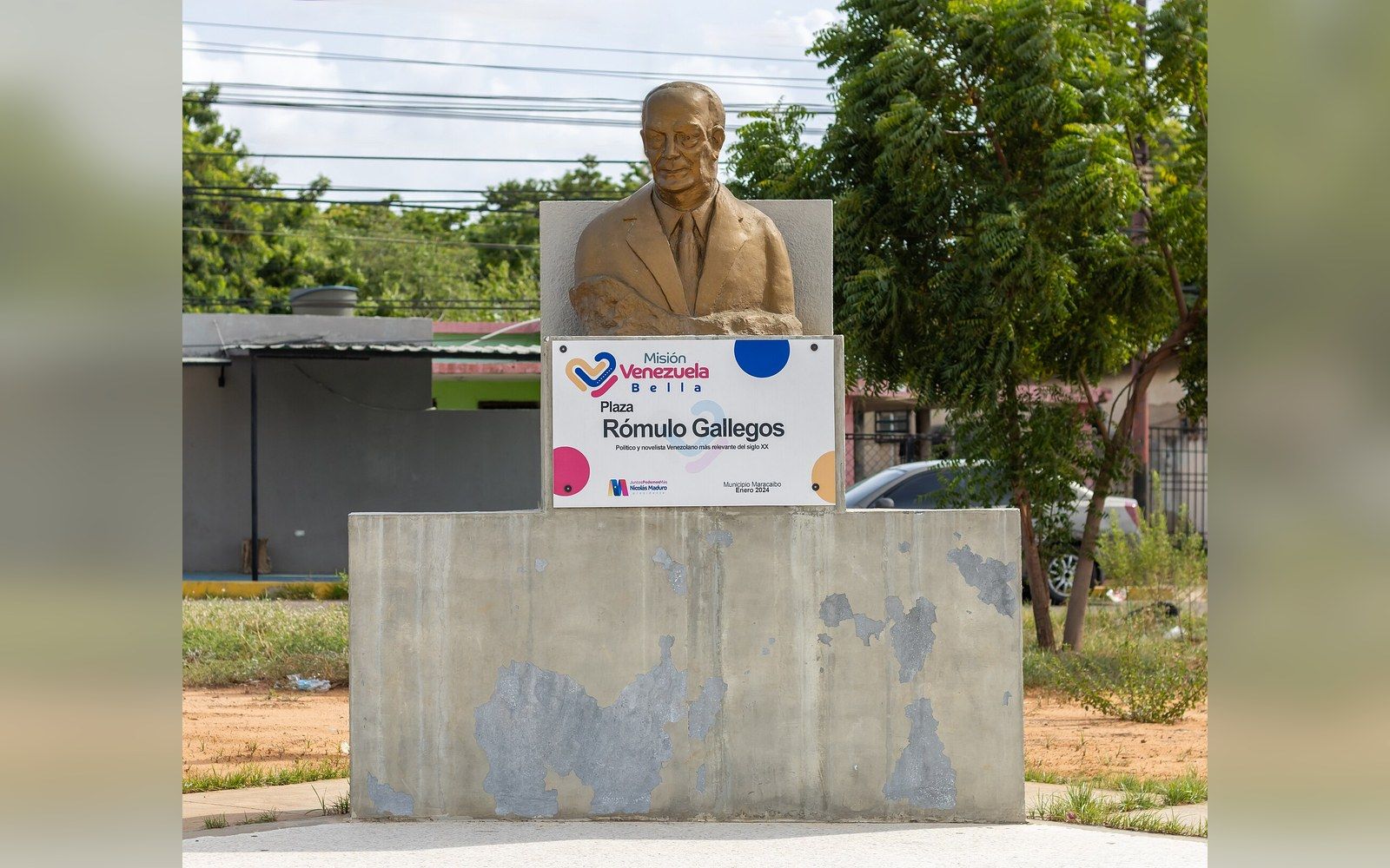 A bronze bust of Rómulo Gallegos on a weathered concrete pedestal with a plaza sign